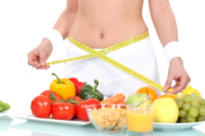 Gadis mengukur pinggang terhadap latar belakang makanan